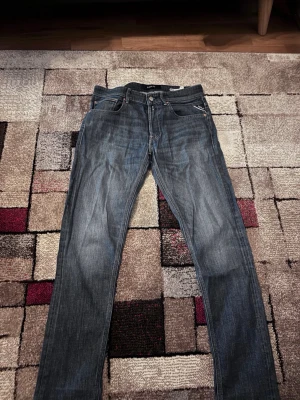 Blå Replay Willbi jeans regular slim - Säljer ett par blå Replay Willbi jeans i regular slim fit. Klassisk femficksmodell med snygga kontrastsömmar och Replay-logga vid fickan. Jeansen har rak passform och är tillverkade i slitstarkt denimtyg. Perfekta för dig som gillar stilrena och tidlösa jeans. Jeansen har ett slitage mellan benen men det är inte så jätte tydligt. Om ni undrar något eller vill ha tydligare bild så kan ni kontakta mig!