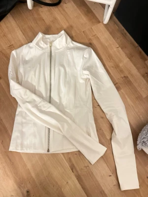 Vit sporty jacka från Gina Tricot XS - Säljer en vit, figursydd sporty jacka från Gina Tricot i storlek XS. Jackan har hel dragkedja framtill, säljer pga för stor 