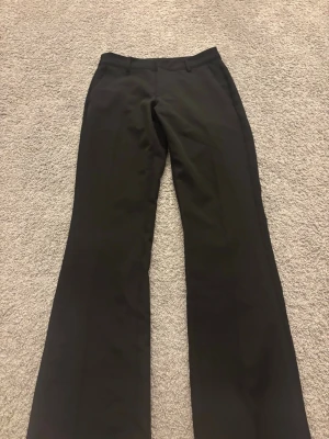 Svarta bootcut kostymbyxor Bik Bok - Säljer ett par svarta kostymbyxor från Bik Bok i storlek 34. Byxorna har bootcut-modell med utsvängda ben, bälteshällor och diskreta bakfickor. Perfekta till en snygg och clean look.