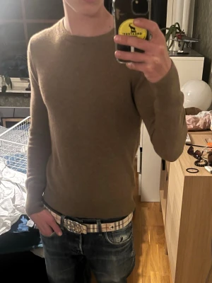 Beige 100% cashmere tröja Uniqlo - Säljer en stilren uniqlo beige cashmir stickad tröja med rund halsringning. Tröjan har en slim passform och är långärmad, perfekt för kyligare dagar. Materialet är mjukt och skönt, vilket gör den riktigt nice att ha på sig över en t-shirt eller skjorta. Öppen för 