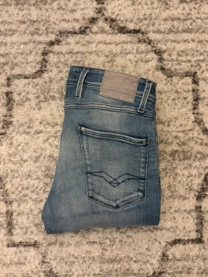 Replay anbass - Säljer ett par riktigt snygga Replay anbass i storlek 30/32, dessa jeans har en ända liten defekt som är att själva R på bakfickan har gått av. Annars är jeansen väldigt fräscha!