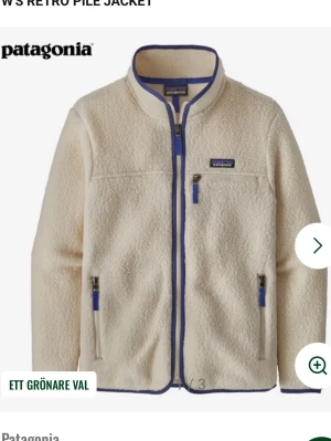 Vit fleecejacka från Patagonia - Säljer en krämvit fleecejacka från Patagonia med blå detaljer och dragkedjor. Jackan har hög krage, tre fickor med dragkedja och en mysig teddystruktur. Perfekt för kalla dagar och riktigt skön att ha på sig.