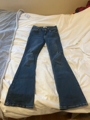 Blå bootcut jeans från Gina tricot  - Snygga blå jeans från Gina tricot med klassisk femficksdesign och bootcut-ben. Jeansen har låg midja och är tillverkade i mjukt denimtyg som sitter skönt.