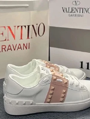 Valentino Rockstud sneakers i vitt och rosa - Säljer ett par vita Valentino Rockstud sneakers med ljusrosa band och ikoniska nitar på sidan och hälen.SKRIV FÖR EGNA BILDER!! Använda 2-3 gånger 
