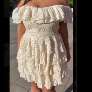 Vit offshoulder spets studentklänning  - Supersöt kort vit klänning i spets med volanger och offshoulder-modell. Perfekt till studenten☺️då det finns en underkjol som sitter ihop med klänning, de gör satt man kan röra sig frit utan problem 😌Klänningen har flera lager i kjolen och en bred volang upptill. Aldrig använt, prislappen är även fortfarande på. Dragkedjan finns på sidan av klänningen under armen❤️ klänningen finns även inte att hitta längre på asos hemsida. 