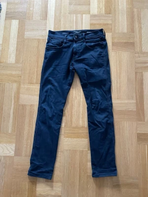 Replay Anbass Hyperflex mörkblå jeans - Säljer ett par Replay Anbass Hyperflex jeans i mörkblå färg. Modellen har klassisk femficksdesign, normal passform och raka ben. Materialet är stretchigt och bekvämt, perfekt för dig som vill ha både stil och rörelsefrihet. Midjan är normal och tyget är mjukt.