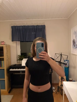 Svart croppad t-shirt från Zara - Säljer en svart croppad t-shirt från Zara i storlek S. T-shirten har korta ärmar och en tight passform och passar mig som brukar ha XS. Den är oanvänd.