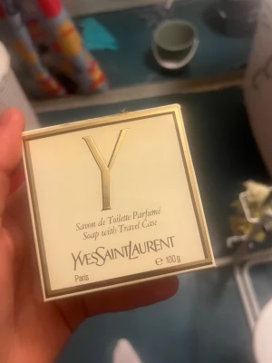 Yves Saint Laurent parfymtvål 100g - Lyxig parfymtvål från Yves Saint Laurent i serien Y. Kommer i en elegant vit och guldig ask med tillhörande reseetui. Tvålen är ljusgul och har YSL-loggan ingraverad. Perfekt för dig som vill ha en exklusiv doftupplevelse i badrummet.
