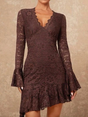 Brun spetsklänning med volang - Snygg brun kortklänning i spets med långärmade ärmar och v-ringad. Klänningen har volangdetaljer vid nederkant och ärmar, samt ett blommigt spetsmönster som ger en romantisk vibe. Perfekt för dig som gillar detaljer och vill sticka ut.