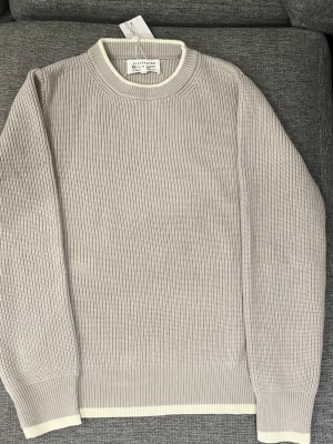 Maison Margiela stickad tröja (ny) - Säljer en beige stickad tröja från Maison Margiela. Tröjan har en klassisk rund hals och långärmad passform, perfekt för dig som gillar stilrena och minimalistiska plagg. Passar M/L