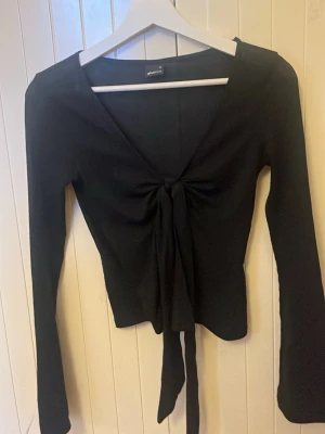 Svart knyt kofta - Säljer en långärmad svart tröja som man knyter där fram. Den är öppen så man kan ha ett linne under om man vill. Tunnt material som är väldigt skönt. Säljer pga låg användning.💗