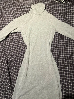 Grå långärmad klänning Forever 21 - Mjuk och enkel grå långärmad klänning från Forever 21 med polokrage. Klänningen har en rak passform och är tillverkad i ett stretchigt material som känns bekvämt mot huden. Perfekt för dig som gillar minimalistisk stil.