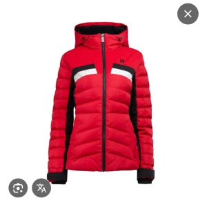 8848 Skidjacka, Röd pufferjacka med huva - Snygg röd pufferjacka från 8848 Altitude med svarta och vita detaljer över bröstet. Jackan har huva, dragkedja framtill och svarta paneler längs sidorna och ärmarna. Perfekt för kalla dagar och har en sportig look. Köpt för 2 år sedan, ca 3400kr