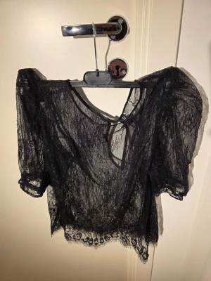 Svart spetsblus med puffärmar  - Blus köpt på H&M för några år sedan. Har använts ca. 2 gånger. Ryggen har en liten öppen detalj.