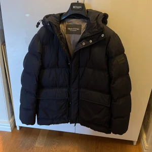 Vinterjacka Marc o’Polo - Varm jacka i mörkblått, använd en säsong. Inga skador eller flåckar. Stor i storleken. Personen som har jackan på bilderna är 180 cm lång. 
