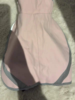 Ljusrosa regnjacka för hunden.  - Säljer en ljusrosa regnjacka för en hund. 2 gummiband vid bakre benen som man kan sätta fast där så att man är säker på att jackan sitter fast. 