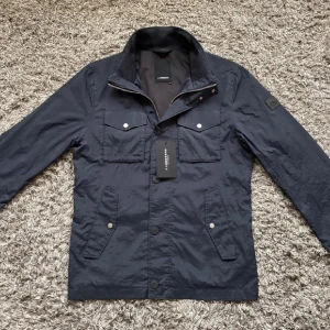 Marinblå vindjacka från J.Lindeberg - Säljer en riktigt fet j.lindeberg field jacketen! ✨Skick: 8/10 lite smått smutsig men borde gå bort i tvätt🙌🏻⭐️STORLEK M!⭐️NYPRIS=4000kr✨Gör gärna av er om ni har några funderingar ✨✨