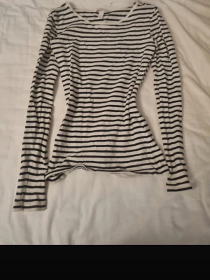Randig långärmad topp från H&M XS - Säljer en vit och svart långärmad topp från H&M i storlek XS. Toppen har ett klassiskt randigt mönster och är figurnära med rund halsringning. Jätteskön