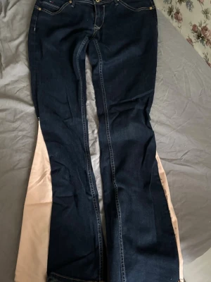 Bootcut jeans med rosa bootcut - Mörkblå jeans från Tommy Hilfiger! Dom är lågmidjade med på sytt tyg som gör dom bootcut. Dom har blivit lite dåligt sydda som man ser på bild 2. Dom är snygga och unika! Pris kan diskuteras och bara att fråga om fler bilder om det önskas! 