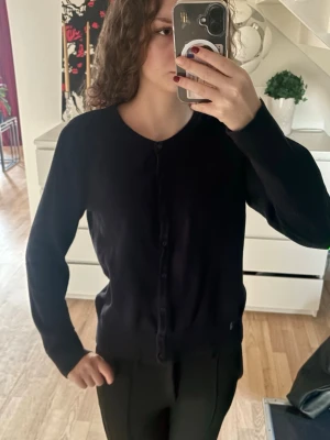 Svart kofta i bomull med knappar - En klassisk svart kofta med rund hals och knäppning framtill. Koftan är i mjuk bomull och ifrån hm i storlek M men är som en S. Den är marinblå inte svart!