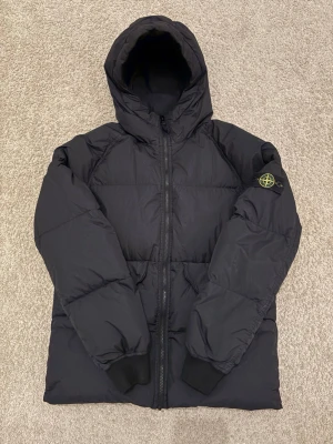 Stone Island vinterjacka  - Säljer en Stone Island vinterjacka som köptes 15 februari på NK. Jackan är använd ytterst få gånger och är praktiskt taget helt ny. Storleken är 14 years och passar bra för någon som är runt 165-170cm lång +/- 5cm. 
