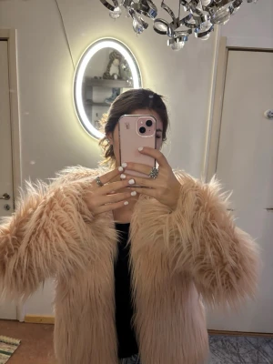 Beige fluffig pälsjacka - Säljer en superfluffig och långhårig beige / rosaaktig pälsjacka med oversized känsla. Jackan har långa ärmar och är tillverkad i fuskpäls💓💓