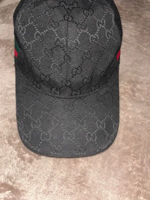 Svart keps  - Säljer en svart keps med röd och grön aktigt mönster vid sida! Pris går att diskurera.