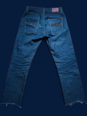 1 of 1 Nudie steady eddie sample - Detta par är helt unikt och är en 1 of 1 sample på nudies gamla modell steady eddie som inte säljs längre. Dessa tillverkades 10e april 2013, och har alltså snart 13 år på nacken. Skicket är bra trots detta och har endast liten fläck i vänster benveck, annars inget att anmärka på. De har blivit förkortade, men det är ingen "defekt" på det viset.  Mått: Storlek enligt etikett: 30/32 | Midja:40cm | Längd:97cm | Benöppning:19cm | Lår:29cm | Innersöm:72cm. Hör av er vid frågor!