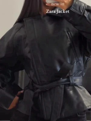Svart skinnjacka med bälte från Zara - Snygg svart skinnjacka från Zara med coolt bälte i midjan. Jackan har en modern, loose passform och långärmade ärmar. Perfekt för dig som vill ha en edgy look med stilrena detaljer. Den trendiga zara jackan, använd 1 gång!