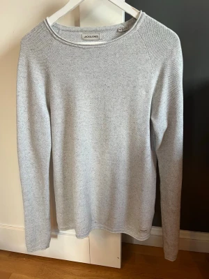 Ljusgrå stickad tröja från Jack & Jones - Säljer en stilren ljusgrå stickad tröja från Jack & Jones. Tröjan har rund hals och långa ärmar. Enkel design som funkar till många olika outfits. Materialet är mjukt och bekvämt. 