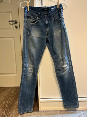 Replay slim jeans med slitningar - Snygga blå jeans från Replay i slim fit-modell med slitna detaljer och tvättad färg. Normal midja och raka ben. Materialet är jeans med lite stretch för skön passform. Perfekt för dig som gillar en avslappnad och trendig stil.