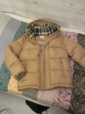 Beige pufferjacka från Burberry - Hej! Säljer en puffer jacket från burberry. Beige färg. Riktigt snygg. Armarna går att ta av för att omvandla till en väst. Storlek S. Riktigt skön. Skriv om ni har funderingar. 