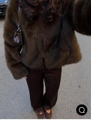 Mörkbrun pälsjacka från Gina Tricot - Säljer en fluffig och mjuk mörkbrun pälsjacka från Gina Tricot. Jackan har rund halsringning, långa ärmar och stängs framtill. Perfekt för dig som vill ha en trendig och varm look under kyliga dagar. Jackan är helfärgad och har en klassisk, rak passform.