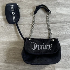 Svart axelväska Juicy Couture - * Axelväskan Kimberly från Juicy Couture i svart velour * Helt ny * Stilren och praktisk axelväska med en elegant klaffstängning * Har en justerbar rem som låter dig välja hur du vill bära den * Storlek i cm: 25x9x17 