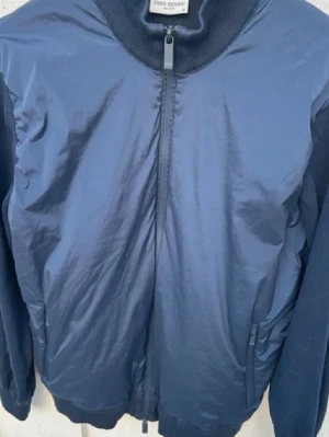 Mörkblå cardigan från John Henric - Snygg mörkblå jacka John Henric med ribbad krage och muddar. Jackan har dragkedja framtill och sidofickor med zip. 