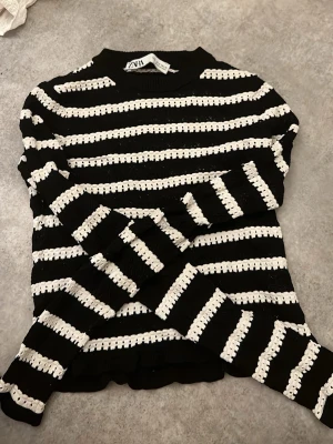 Svartvit randig stickad tröja Zara - Säljer en svart och vit stickad tröja från Zara i storlek S. Tröjan har ett randigt mönster med breda vita ränder och långärmade ärmar. Rund halsringning och mjukt stickat material som känns skönt mot huden. Perfekt för dig som gillar klassisk stil med en twist.
