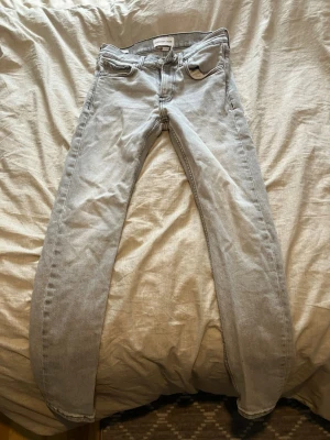 Calvin Klein jeans - Snygga ljusgrå jeans från Calvin Klein Jeans i modellen Slim Taper. Klassisk femficksdesign med CK-logga på bakfickan och metallknapp framtill. Jeansen har smal passform och är tillverkade i mjukt bomullsmaterial för en skön känsla.