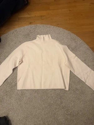 Vit polotröja från & Other Stories - Säljer en stilren vit polotröja från & Other Stories i storlek S. Tröjan har lång ärm, hög krage och är i ett mjukt material som känns skönt mot huden. Perfekt att styla med jeans eller kjol för en clean look.