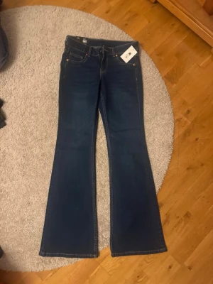 Mörkblå bootcut Lågmidjade jeans strl 38 - Snygga mörkblå jeans med bootcut-modell och klassiska kontrastsömmar. Byxorna har fem fickor och normal passform. Perfekta till sneakers eller boots och tillverkade i mjukt jeansmaterial.