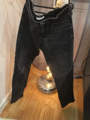 Svarta jeans med tvättad look - Snygga svarta jeans med tvättad effekt och klassisk femficksdesign. Jeansen har normal passform och raka ben, perfekta för en avslappnad stil. Tillverkade i mjukt denimtyg som ger en skön känsla hela dagen.