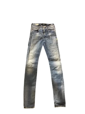 Replay ljusblå jeans straight fit - Säljer ett par ljusblå jeans från Replay med klassisk femficksdesign och raka ben. Jeansen har snygga slitningar och en diskret tvättad look. Perfekta för dig som gillar en enkel men stilren vibe. Materialet är jeans och passformen är normal.