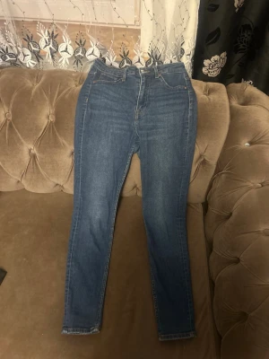 Blå skinny jeans med hög midja - Snygga blå skinny jeans med hög midja och klassisk femficksdesign. Jeansen har en smal passform och är perfekta för dig som gillar en enkel och stilren look. Tillverkade i mjukt denimtyg som sitter bekvämt hela dagen.