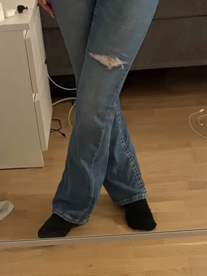 Blå bootcut jeans med slitning - Säljer ett par ljusblå bootcut jeans med slitning och spets. Jeansen är storlek 164 tall (sitter som XS/34). Har själv gjort hålen och sytt in spets🩷