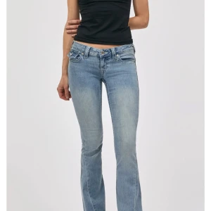 Ljusblå bootcut jeans från True Religion - Säljer ett par ljusblå bootcut jeans från True Religion med klassiska kontrastsömmar och ikoniska fickdetaljer bak. Jeansen har låg midja och är tillverkade i mjukt denim med stretch för skön passform. Lite slitna längst ner men inget som märks