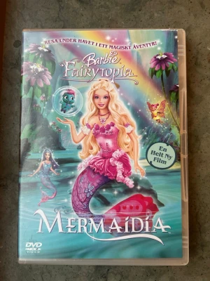 Barbie mermadia dvd - Följ med Elina på hennes fortsatta resa under vatten i uppföljaren till Fairytopia i denna uppföljare som beger sig Elina till Mermaidia för att rädda sin vän, havsmannen Nalu. Genre: Animerad. Speltid: Ca 1 tim 14 min.  Finns på språk: Svenska, Engelska, Finska   OBS!! skivorna är begagnade så det kan förekomma repor/hairlines på skivorna, men då jag kollar igenom alla filmer jag säljer garanterar jag att alla funkar felfritt om inget annat står! :)
