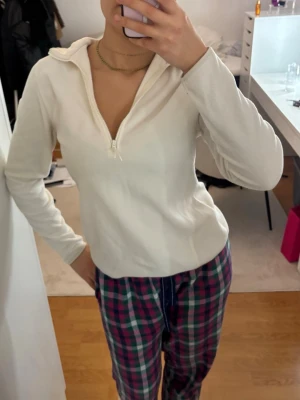 Vit fleece polotopp med half zip - Mysig vit polotopp i fleece med lång ärm och half zip framtill. Perfekt för lager på lager och chill dagar. Enkel och stilren design utan synliga loggor eller mönster.