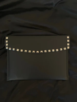 Datorfodral med silver nitar i läderimitation  - Rea - endast 199 kr (ord. pris 249 kr)! Stilrent datorfodral tillverkat av veganskt läder i vattentätt material. Fodralet stängs med knapp. Fodralet skyddar din dator effektivt samtidigt som det ger din outfit en extra touch. ⚜️ Storlek: 34 × 25 cm – passar svarta HP Chromebooks och andra datorer i liknande storlek. Förbeställning postas senast efter 7 dagar! 📦