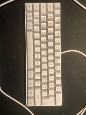 Kompakt vit mekanisk tangentbord - Snyggt kompakt mekaniskt tangentbord i vit plast med nordisk layout, RGB och USB-anslutning. Perfekt för dig som vill ha ett minimalistiskt skrivbord och gillar mekaniska tangenter. Tangentbordet har funktionstangenter och tydliga bokstäver.