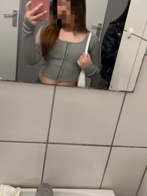 En grå cardigan från h&m - Säljer en grå ribbad cardigan med croppad passform och långa ärmar. Tröjan har en djup, rundad urringning och dragkedja framtill. Perfekt att styla med jeans eller kjol för en trendig look.