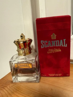 Scandal Pour Homme Jean Paul Gaultier - Scandal Pour Homme från Jean Paul Gaultier är en parfym i en lyxig, fyrkantig glasflaska med en guldfärgad krona som lock. Förpackningen är röd med metallicdetaljer och tydlig logga. Flaskan rymmer 100 ml och har en exklusiv och modern design. MER ÄN HÄLFTEN KVAR, UNGEFÄR 60ml